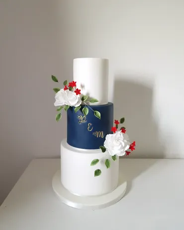 Three-tier navy and white wedding cake with red and white sugar flowers